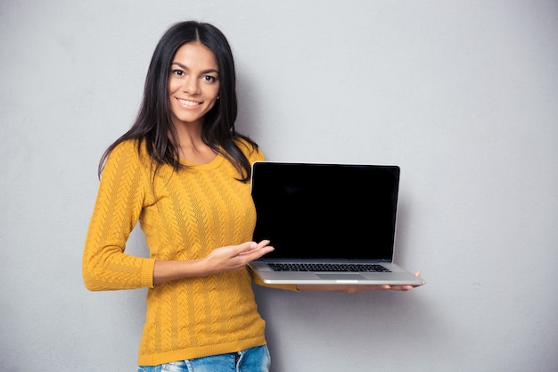 ノートパソコンの画面を示す笑顔の女性