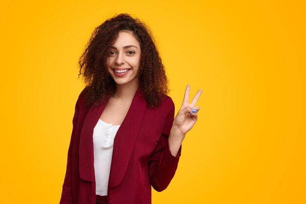 Smiling woman showing peace sign in studio