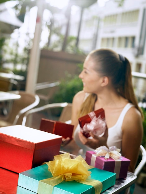 Photo smiling woman sitting by gifts in restaurant