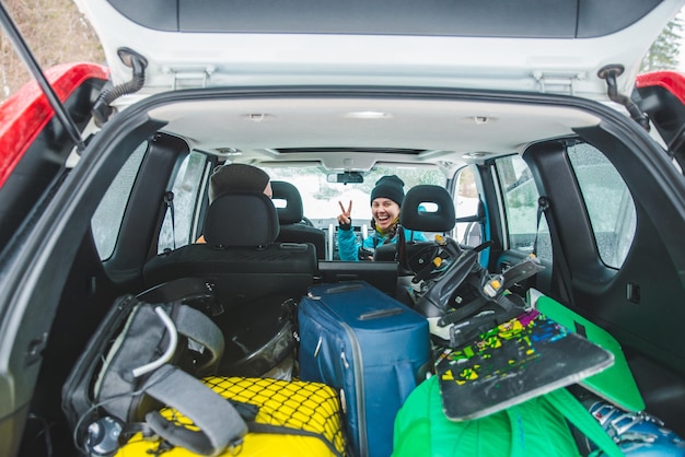 Photo smiling woman sitting in car snowboard in car trunk road trip