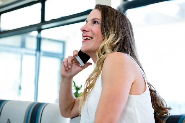 smiling woman sitting on a couch making a phone call