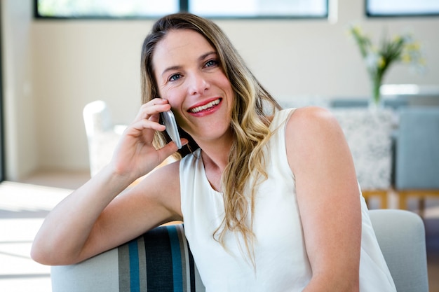 smiling woman sitting on a couch making a phone call