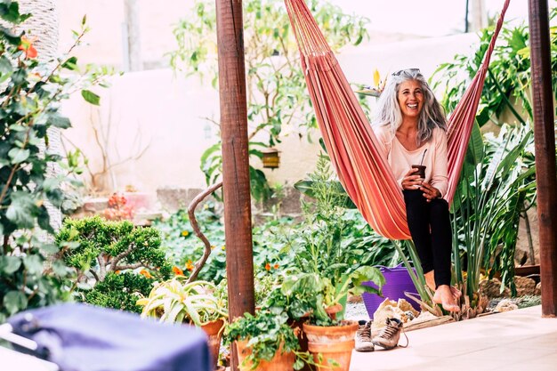 Photo smiling woman sitting on hammock by plants