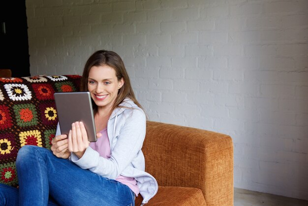 Smiling woman sitting at home with digital tablet