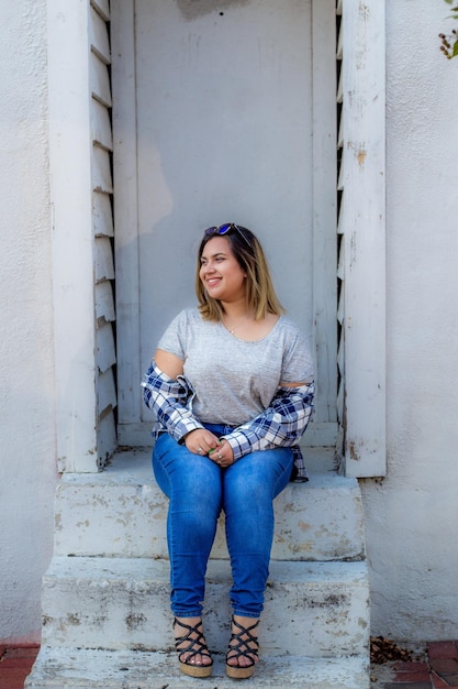 Photo smiling woman sitting at house entrance