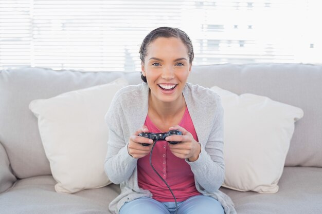 写真 ビデオゲームをするソファーに座っている笑顔の女性