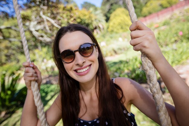 Smiling woman sitting on swing in park