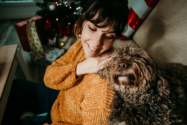 Photo smiling woman sitting with dog at sofa