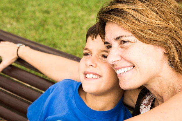 Foto donna sorridente e figlio seduti al parco