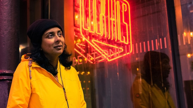 Photo smiling woman standing against illuminated building at night