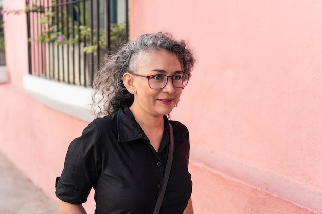 Foto donna sorridente in piedi contro il muro rosa