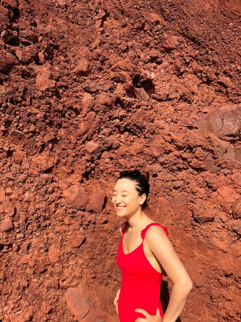 Foto donna sorridente in piedi contro una formazione rocciosa