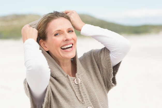 Smiling woman standing on the sand with hood up