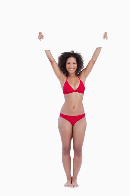 Smiling woman standing upright while holding a blank poster above her head