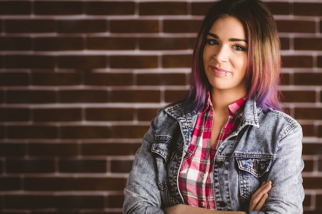 Smiling woman standing with arms crossed against brick wall