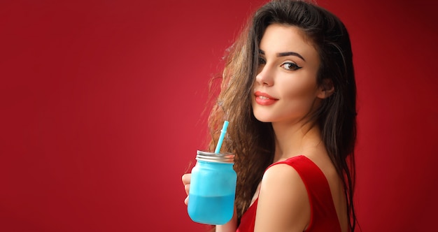 Smiling woman standing with drinking jar in studio