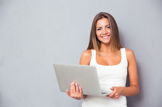 Foto donna sorridente in piedi con il computer portatile