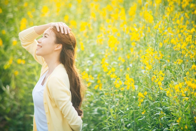 黄色い花の畑に立っている笑顔の女性
