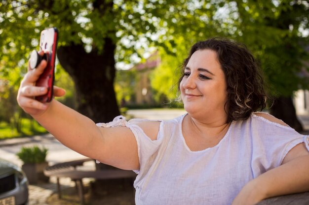 Photo smiling woman on street using mobile and having video call