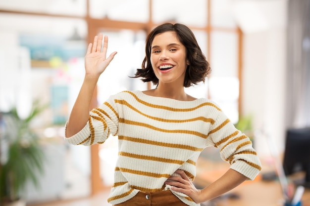 Foto donna sorridente con il maglione a righe che agita la mano