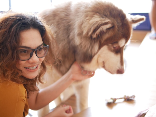 Photo smiling woman stroking dog while looking away at home