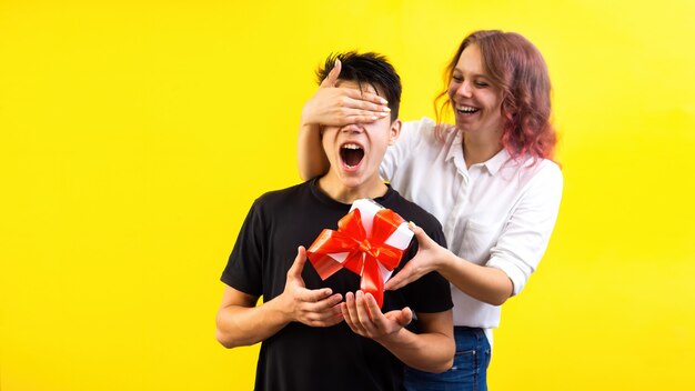 Photo smiling woman surprising a boy with a gift box