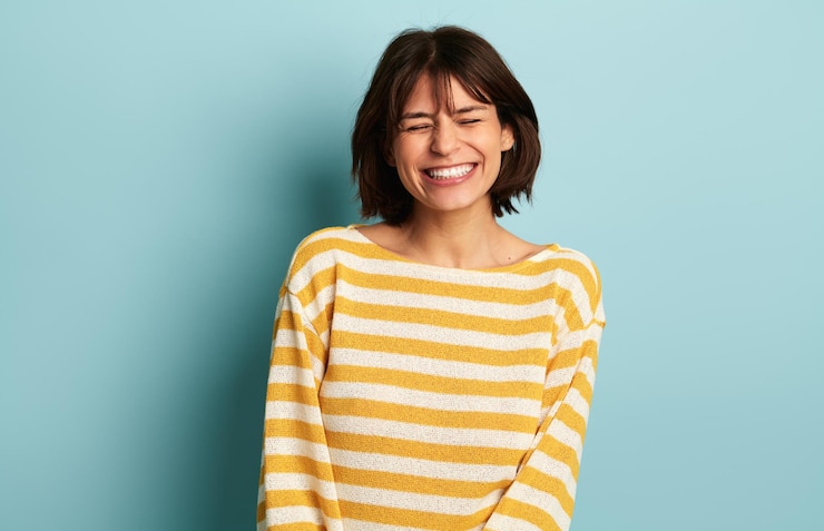 Photo 目を閉じて微笑むセーターを着た笑顔の女性