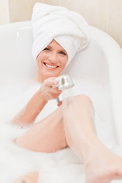 Smiling woman taking a bath with a towel on her head 