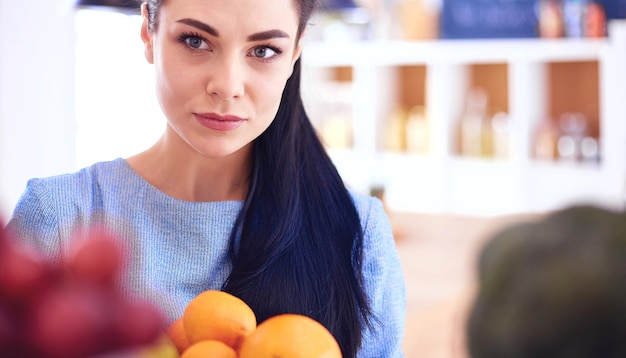 Smiling woman taking a fresh fruit out of the fridge healthy food concept