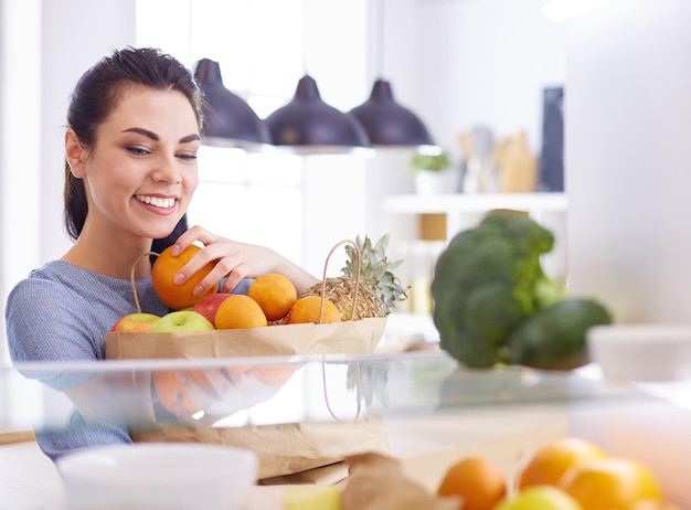 냉장고 건강 식품 개념에서 신선한 과일을 꺼내는 웃는 여자