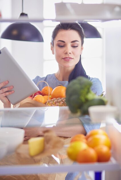 冷蔵庫から新鮮な果物を取り出して笑顔の女性、健康食品のコンセプト