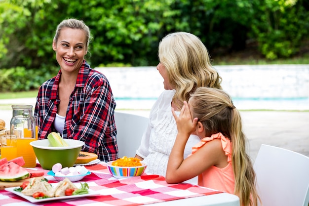 Smiling woman taking to mother and daughter at table