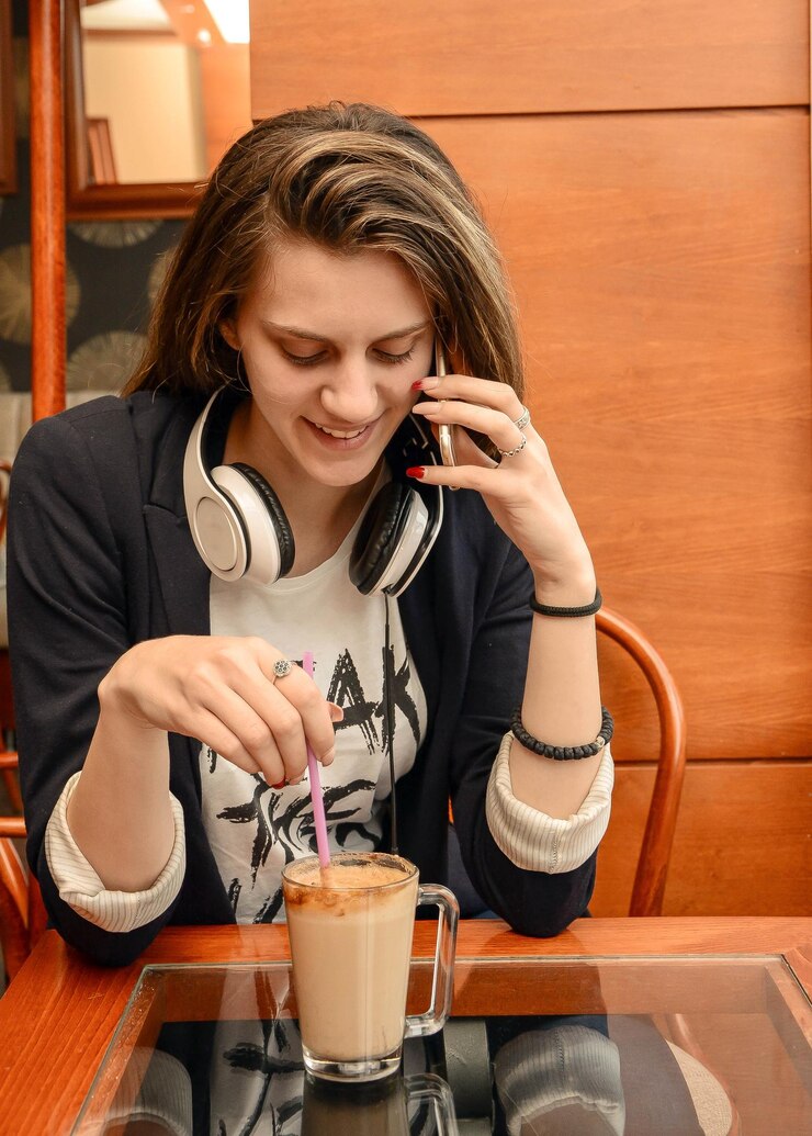 Photo smiling woman talking on smart phone while sitting at table in cafe
