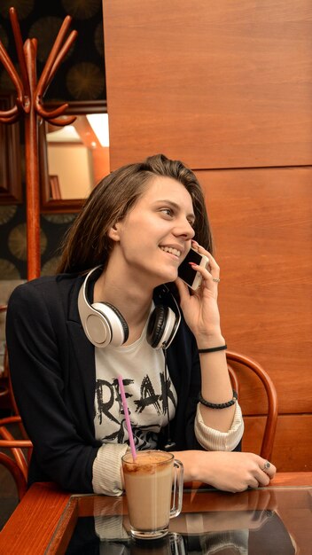 Smiling woman talking on smart phone while sitting at table in cafe