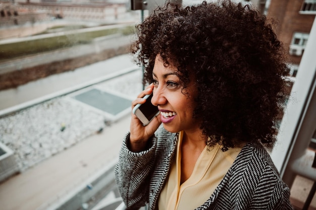 Photo smiling woman talking through phone in city