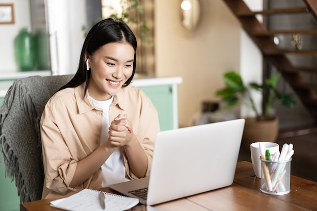 Smiling woman talks online on webinar video chatting having conference with work colleagues from hom...