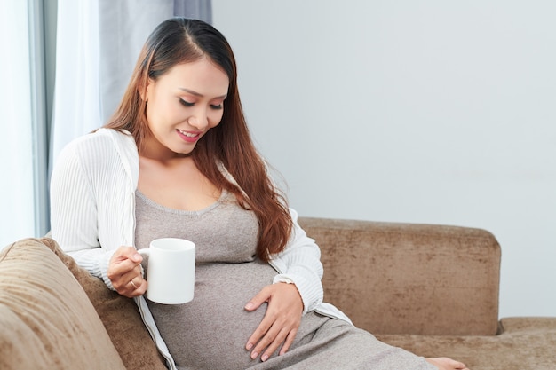 Smiling woman touching her pregnant belly