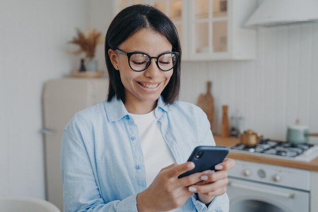 Smiling woman use mobile phone apps order groceries in online store check social networks at home