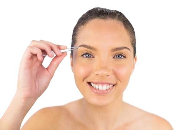 Smiling woman using her tweezers