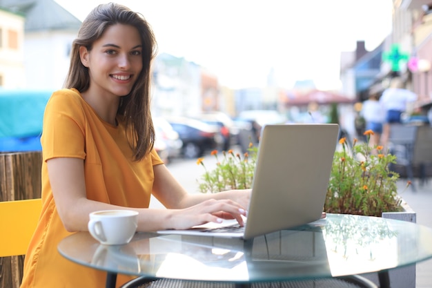 Smiling woman using laptop in cafe. Concept of entrepreneur, businesswoman, freelance worker.