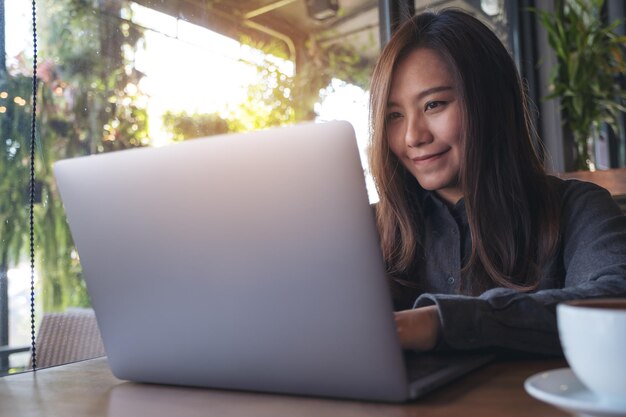 Photo smiling woman using laptop on table