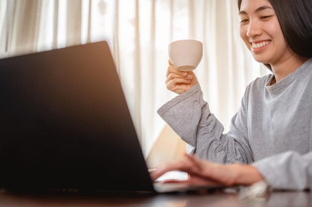 Smiling woman using laptop while having coffee