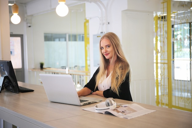 Smiling woman using laptop in work place for small businesses looking to engage audiences and scale content creation can adopt new marketing technology in workspace. Freelancer concept.