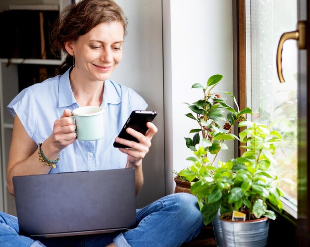 Smiling woman using mobile phone at home