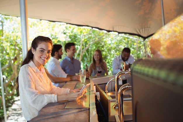 Smiling woman using mobile phone while having a glass of champagne in restaurant