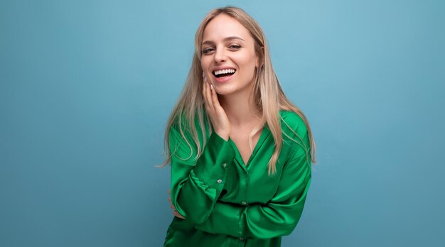 Smiling woman on vacation in green shirt posing on blue studio background