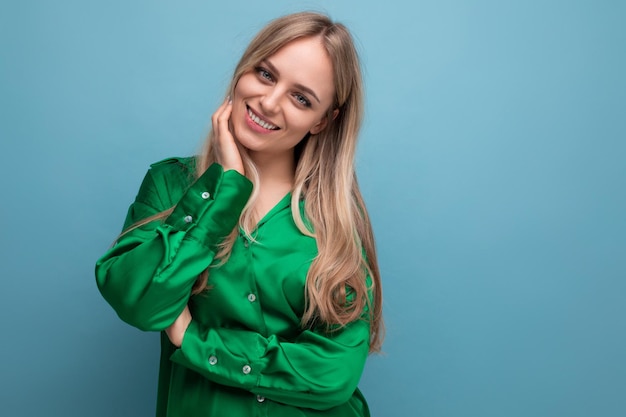 Smiling woman on vacation in green shirt posing on blue studio background