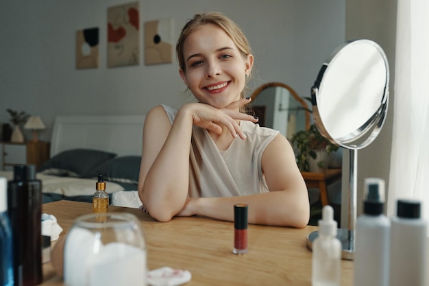 Smiling woman at vanity table surrounded by beauty products
