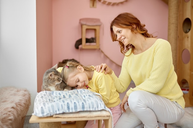 Smiling woman volunteer looking at cute girl petting cat