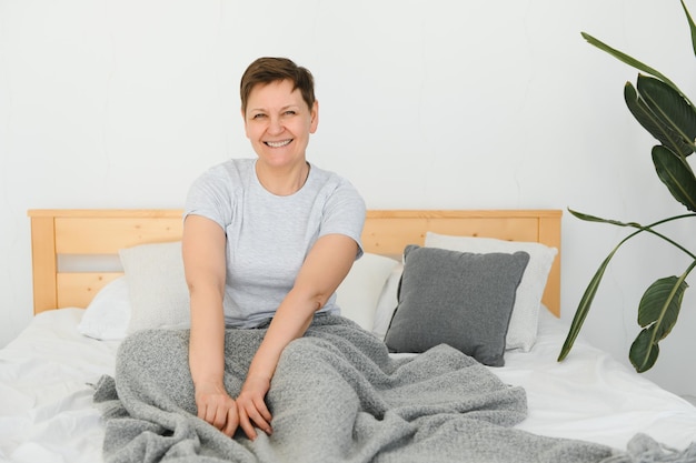 Smiling woman waking up and stretching in bed at morning